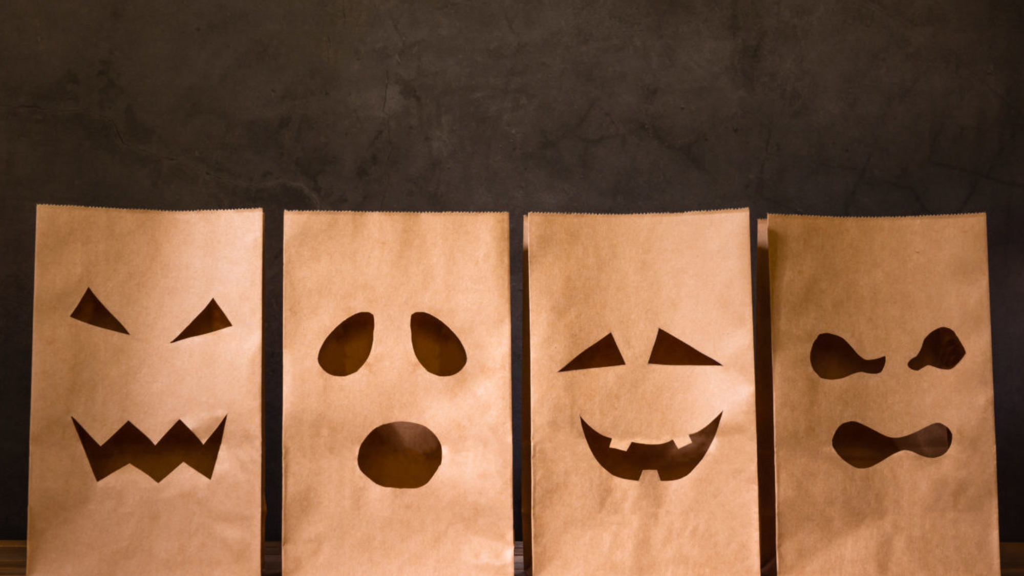 paper bags with scary face on wooden table, halloween concept
